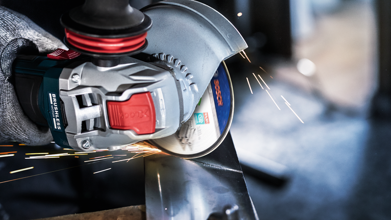 一名佩戴安全設備的人研磨金屬，產生明亮的火花。