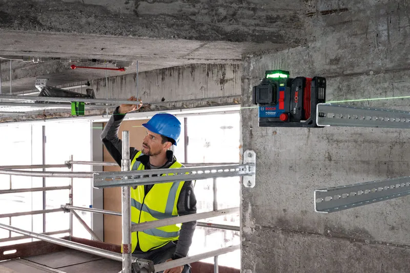 GLL 18V-120-33 CG 一名配戴安全設備的人員使用雷射調平工具對準金屬棒。.