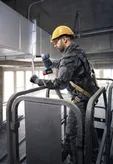 一名佩戴安全設備的人員使用無線電動工具來固定管道。.