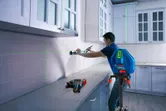 一名工作人員正在使用三腳架上的雷射調平工具調整廚房櫥櫃。