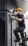 一名配戴安全設備的人員使用電鑽安裝安全攝影機。.