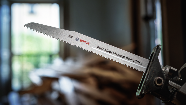 往復鋸片安裝在電動工具上，背景顯示模糊的木屑。