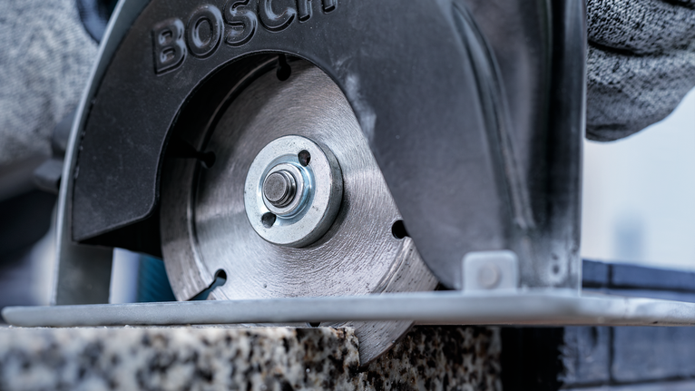 配戴安全裝備的人員使用圓鋸切割石頭。