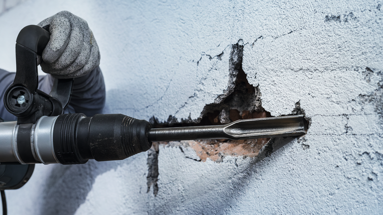 PRO SDS max 鋸齒鏜孔鑿刀,26 x 300 mm 一名佩戴安全設備的人使用旋轉錘鑿牆。