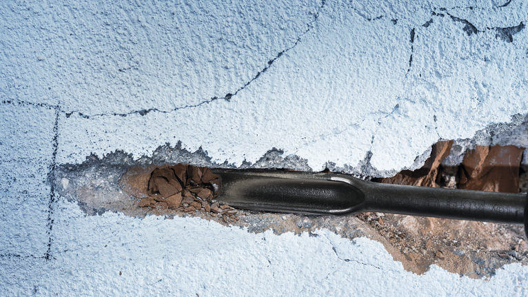 PRO SDS max 鋸齒鏜孔鑿刀,26 x 300 mm 鑿子工具打破了粉刷過的牆壁上的灰泥。