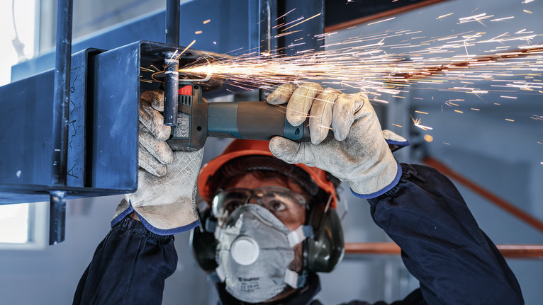 PRO Stainless Steel and Metal 接合切削砂輪片,76 x 1 x 10 mm 配戴安全設備的人研磨金屬,產生火花。