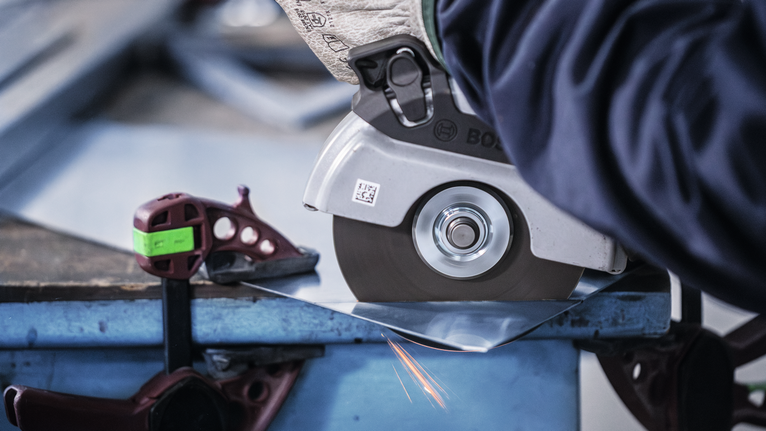 配戴安全設備的人員使用角磨機切割金屬板。