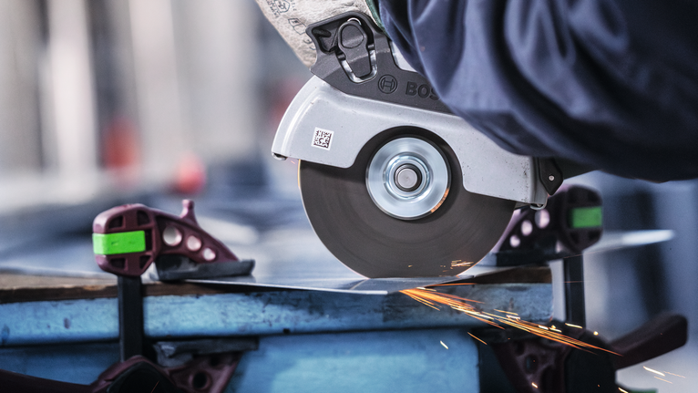 配戴安全設備的人用圓鋸切割金屬板，產生火花。