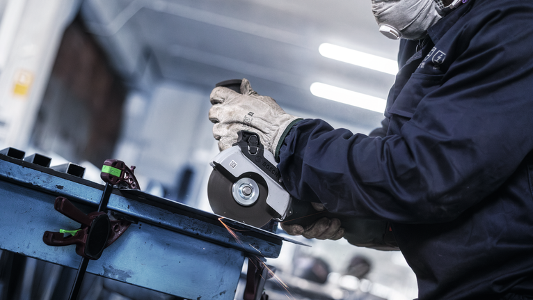 配戴安全設備的人員使用角磨機研磨金屬，產生火花。