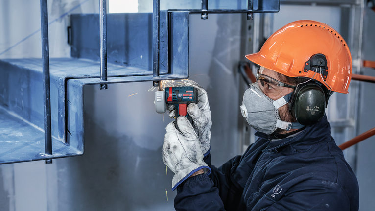 一名配戴安全設備的人正在用電動工具打磨金屬樓梯。