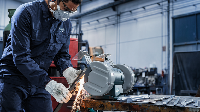 PRO Metal 研磨輪,200 x 25 x 32 mm,G36 一名配戴安全設備的人員在車間的桌上型砂輪機上打磨金屬。