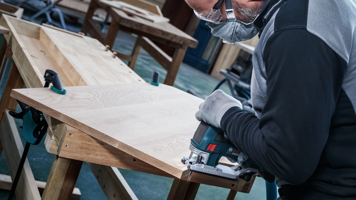 配戴安全設備的人員使用曲線鋸切割木板。