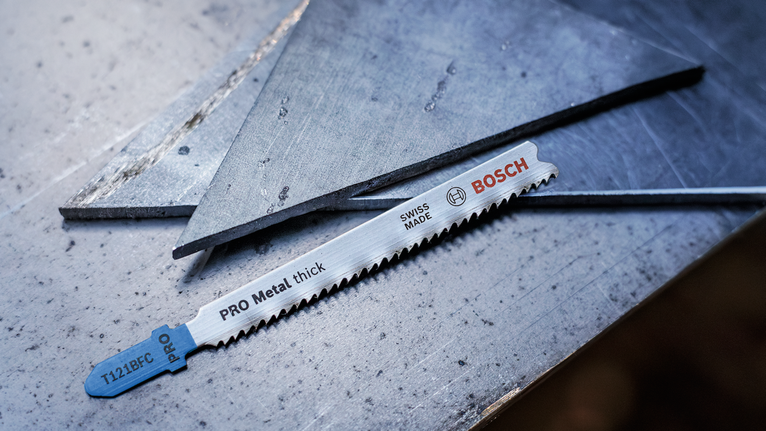 金屬鋸片放置在切割金屬板旁的鋼表面上。