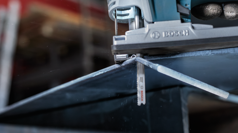 拼圖鋸沿著標記線切割金屬板。