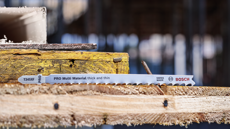 PRO Multi Material 厚薄通用款 T345XF 線鋸片,132 mm,5 件 拼圖鋸刀片放在建築工地堆疊的木板上。