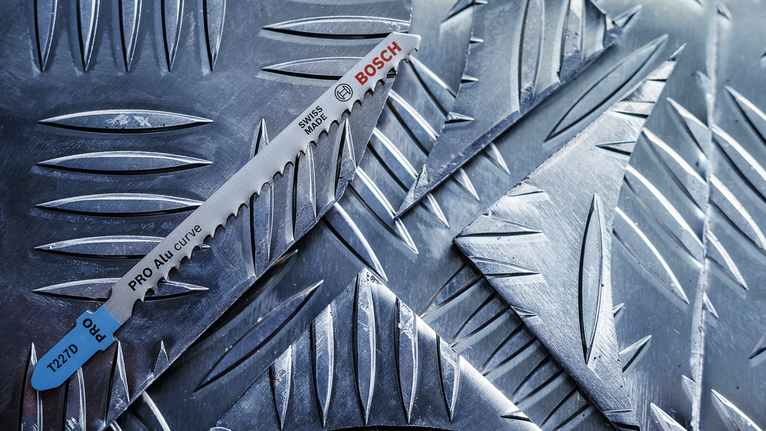 PRO Alu curve T227D 專業鋁材曲線切割款線鋸片,100 mm,5 件組 鋸片放置在有紋理的金屬板上。