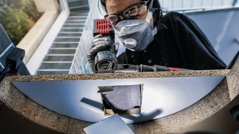 穿著安全設備的人員在木板上鑽孔。