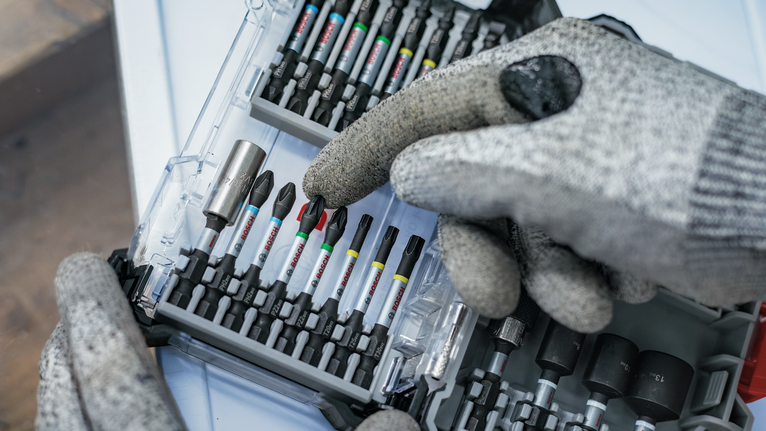 配戴安全設備的人員從有序的工具箱中選擇一個螺絲起子頭。