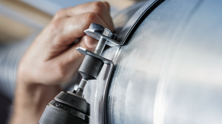 人員使用電動工具將金屬夾固定到管道上。