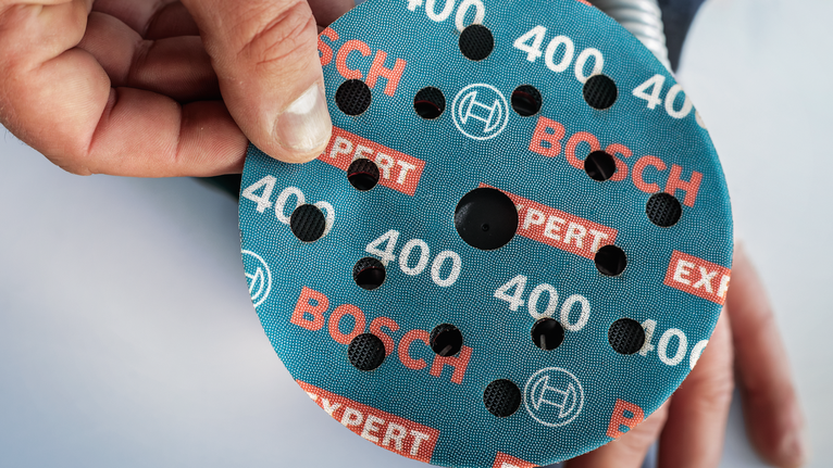 EXPERT O780 箔砂磨砂輪片,125 mm,G60 人員將圓形磨料砂輪放置在工具上。.