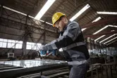 一名配戴安全設備的人員使用電動工具緊固金屬框架上的螺栓。