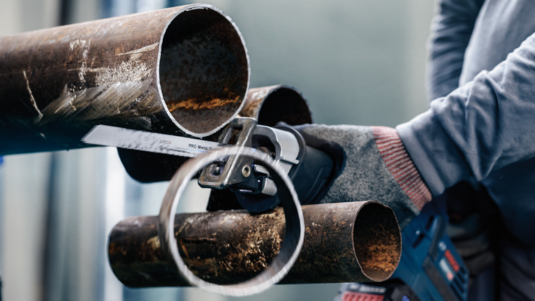 一名配戴安全設備的人用往復鋸切割金屬管路。