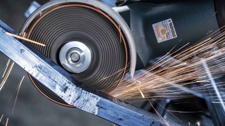 角磨機切割金屬棒，產生明亮的火花。