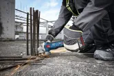 一名配戴安全設備的人員在建築工地上磨鋼筋，產生火花。.