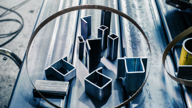 金屬管和型材排列在工作台上的帶鋸條內。.