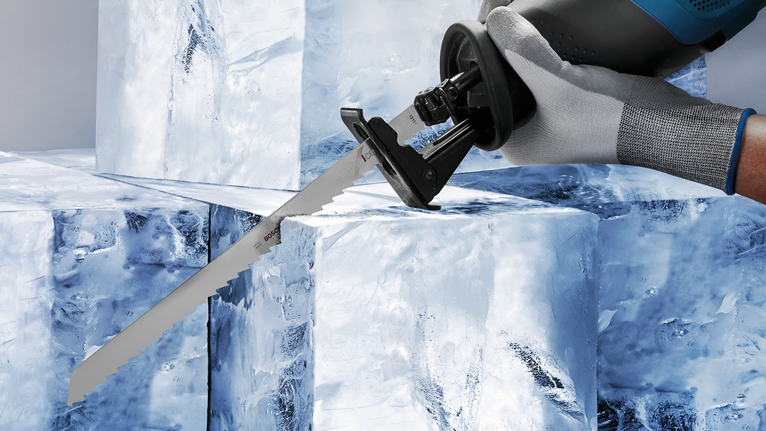 配戴安全設備的人員使用往復鋸切割大冰塊。