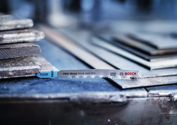 PRO Metal thick and thin T123XF 線鋸片,100 mm,5 件 拼圖鋸刀片放置在車間堆放的金屬板上。