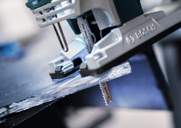 PRO Metal thick and thin T123XF 線鋸片,100 mm,5 件 車間裡,拼圖鋸正在切割一塊深色金屬板。