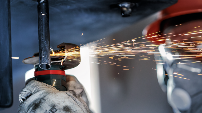 PRO Stainless Steel and Metal 接合切削砂輪片,76 x 1 x 10 mm 配戴安全設備的人員在火花飛濺的情況下研磨金屬管。.