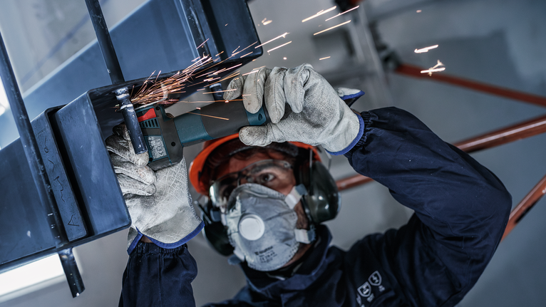 PRO Stainless Steel and Metal 接合切削砂輪片,76 x 1 x 10 mm 一名配戴安全設備的人正在研磨金屬,產生火花。