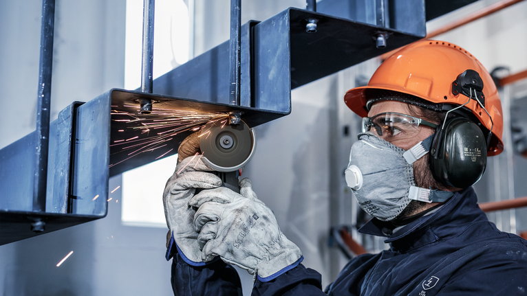 配戴安全設備的人員使用研磨機切割金屬樓梯。