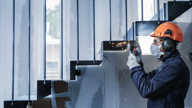 一名配戴安全設備的人磨擦金屬樓梯，產生火花。