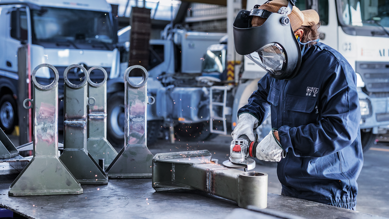 配戴安全設備的人員在工業環境中研磨金屬零件。