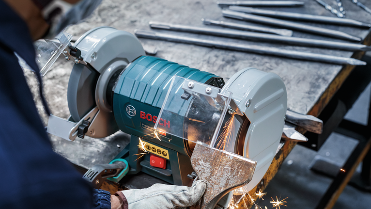 PRO Metal 研磨輪,200 x 25 x 32 mm,G36 一名配戴安全設備的工人正在用桌上型砂輪機打磨金屬零件。.