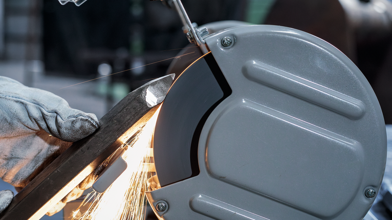 PRO Metal 研磨輪,200 x 25 x 32 mm,G36 一名配戴安全設備的人正在用桌上型砂輪機打磨金屬棒。