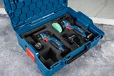 無線拋光機套件，配有電池組和充電器，放在藍色手提箱中。.