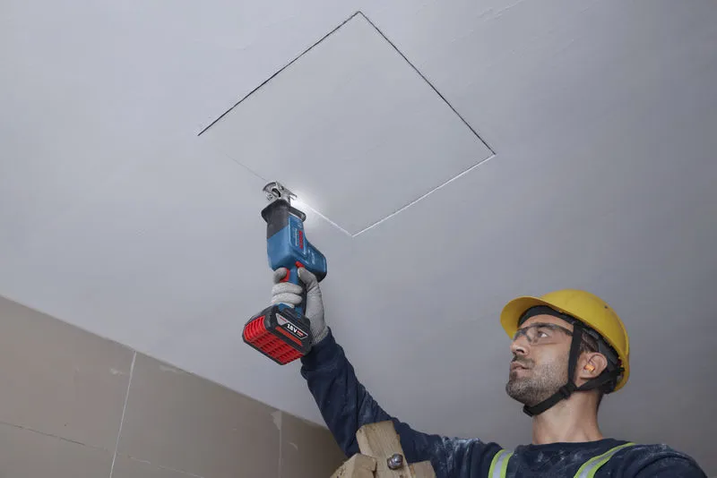 GSA 18V-24 一名配戴安全設備的人員正在用往復鋸切割天花板。.