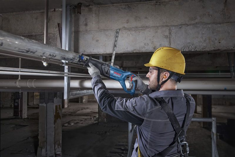 一名配戴安全設備的人員用往復鋸切割金屬管。.