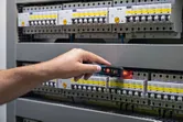 人員使用非接觸式電壓測試儀測試電氣面板。.