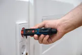 一個人在電源插座附近使用非接觸式電壓測試器。