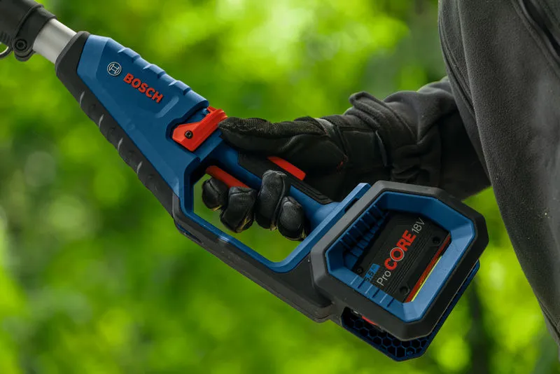 Person wearing safety equipment holds a cordless pole saw outdoors.