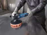 一名佩戴安全設備的人正在使用電動工具來拋光金屬表面。