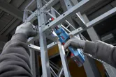 穿戴安全裝備的人員使用無線角鑽在金屬框架上作業。