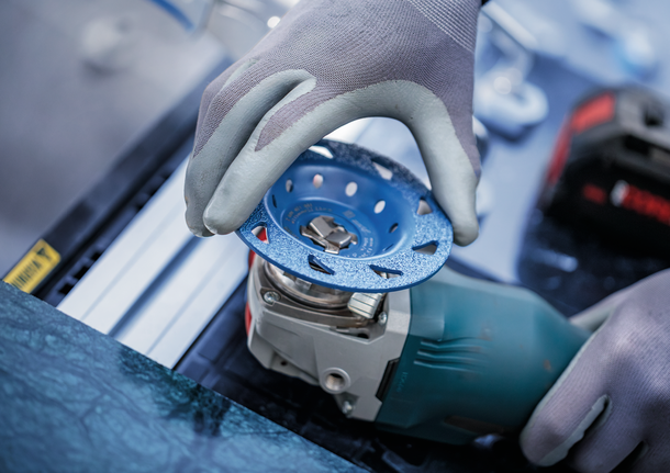 中型超耐久多材質專業款碳化鎢硬質合金研磨盤,平面型,X-LOCK,115 mm,22.23 mm 配戴安全設備的人員將砂輪安裝到電動工具上。.