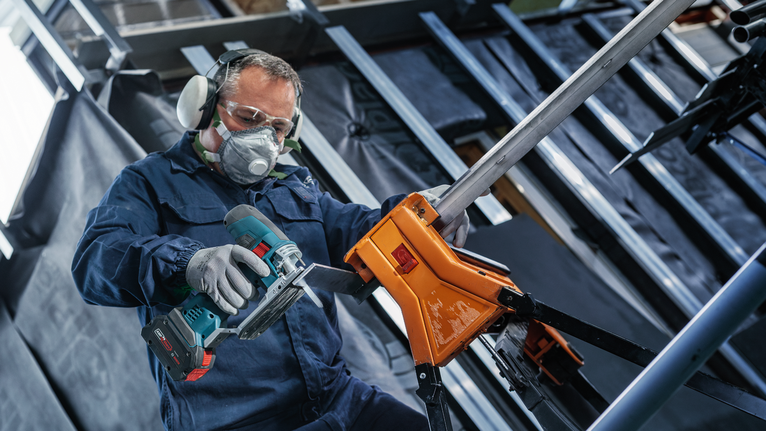 超耐久超厚金屬專業款 T155HHM 線鋸片,3 件 一名配戴安全設備的人員正在使用無線電動工具切割金屬管。