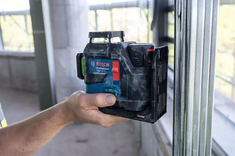 GLL 90-33 XG 一名工人拿著雷射調平工具靠在建築工地的金屬螺柱上。.